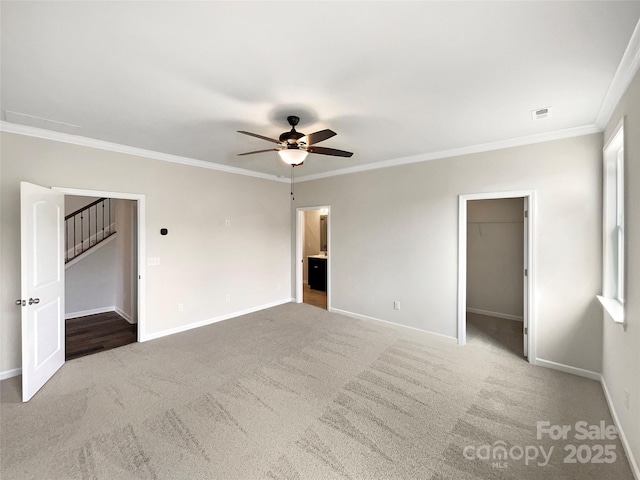 interior space featuring carpet floors, ornamental molding, a spacious closet, and baseboards