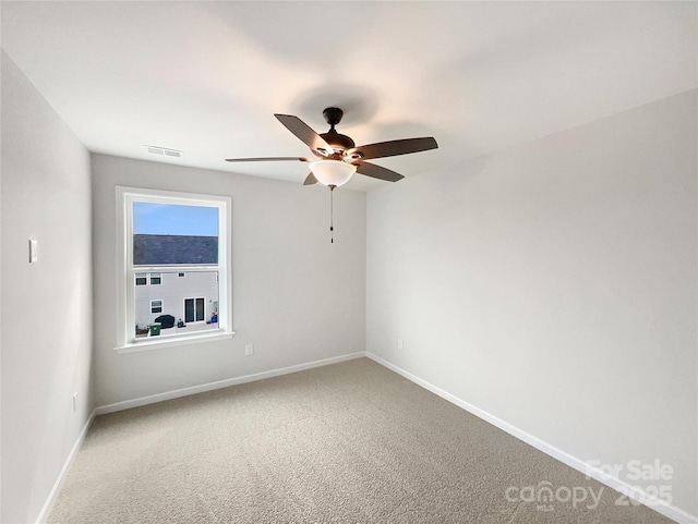 carpeted spare room featuring visible vents, baseboards, and a ceiling fan