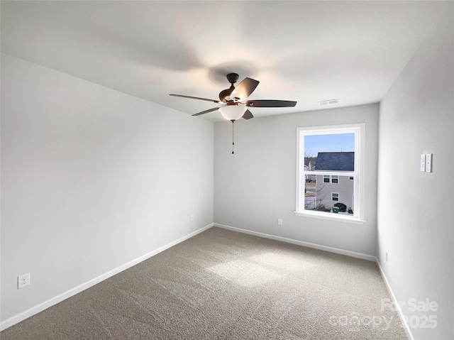 carpeted spare room with a ceiling fan, visible vents, and baseboards