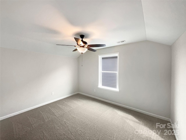 carpeted empty room featuring ceiling fan, baseboards, visible vents, and vaulted ceiling