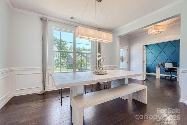 dining area with crown molding, visible vents, dark wood finished floors, and a decorative wall