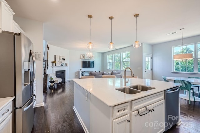 kitchen featuring dark wood-style floors, visible vents, a glass covered fireplace, a sink, and stainless steel fridge