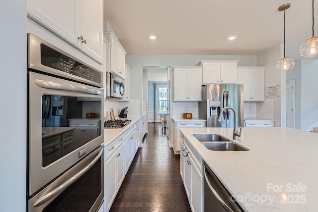 kitchen with backsplash, white cabinetry, stainless steel appliances, and a sink