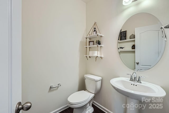 bathroom with a sink, toilet, and baseboards