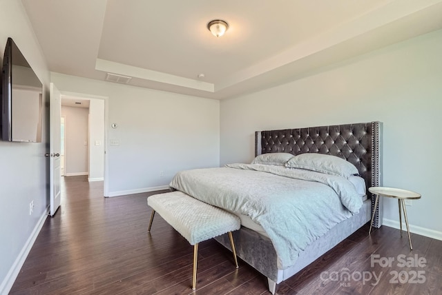 bedroom featuring dark wood-type flooring, a raised ceiling, visible vents, and baseboards