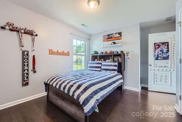 bedroom with visible vents, baseboards, and wood finished floors