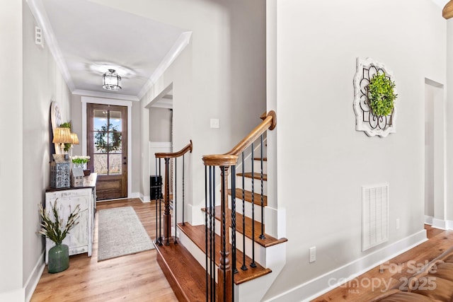 entrance foyer featuring visible vents, crown molding, baseboards, and wood finished floors