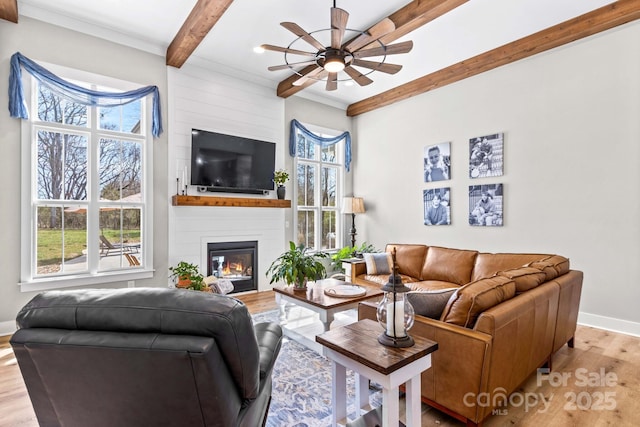 living area featuring ceiling fan, a fireplace, wood finished floors, baseboards, and beamed ceiling