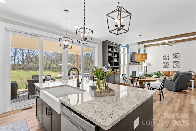 kitchen with dishwasher, decorative light fixtures, light wood-style floors, a fireplace, and a sink