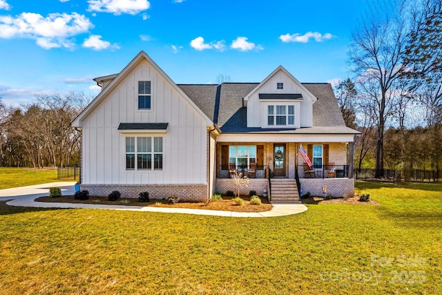 modern farmhouse style home with a porch, board and batten siding, a front yard, and fence