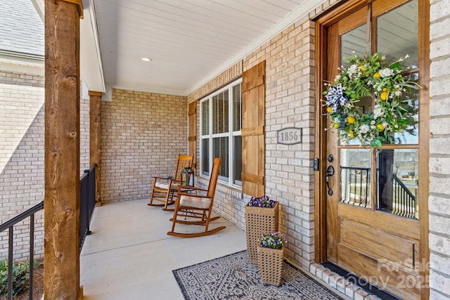 exterior space featuring covered porch and brick siding