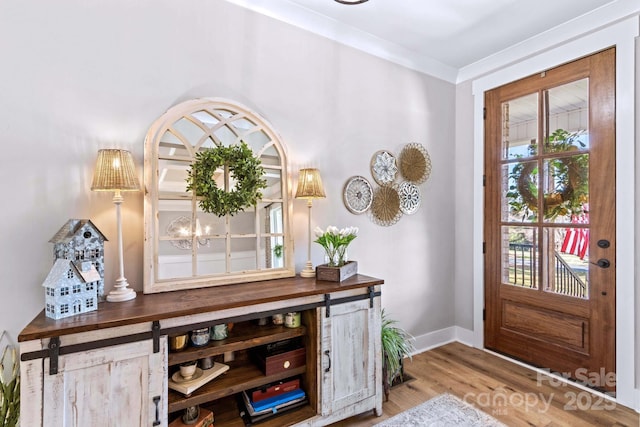 foyer with baseboards, a chandelier, wood finished floors, and ornamental molding