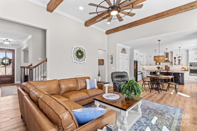 living room with light wood finished floors, visible vents, ornamental molding, beamed ceiling, and stairs