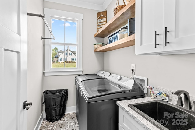 laundry room featuring cabinet space, baseboards, washer and dryer, and a sink