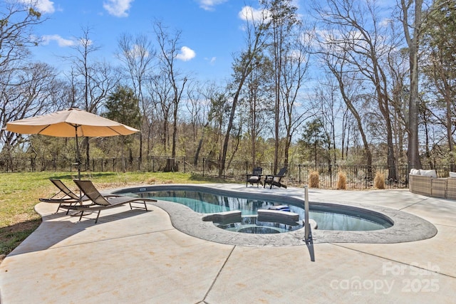 view of swimming pool featuring a patio area, fence, a pool with connected hot tub, and a view of trees