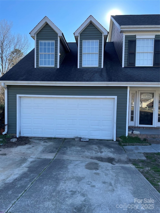 view of front facade featuring a garage, roof with shingles, and driveway