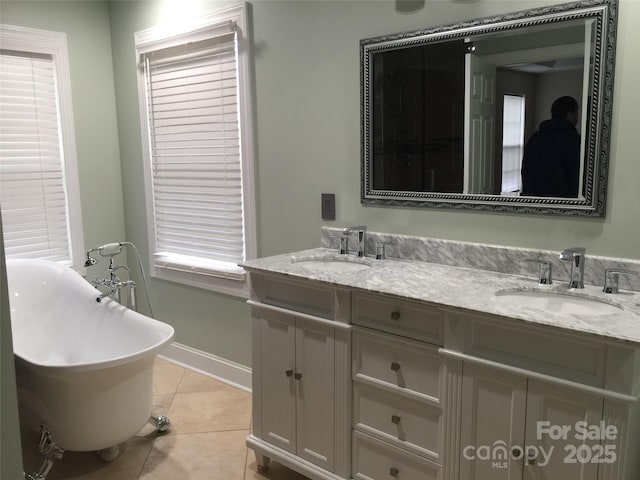 bathroom featuring double vanity, a freestanding tub, a sink, and tile patterned floors