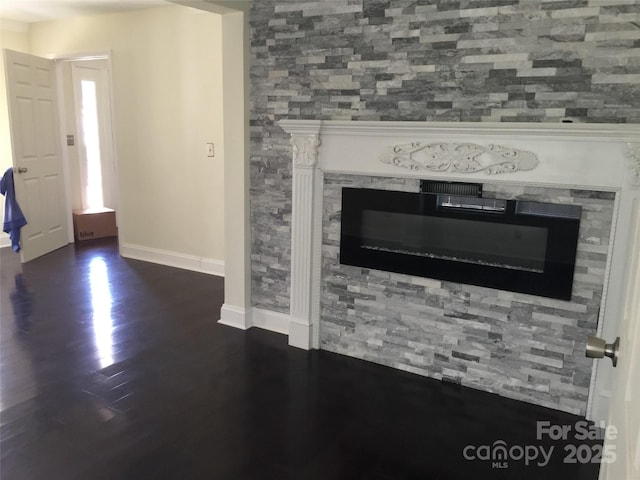 details with a glass covered fireplace, baseboards, and wood finished floors