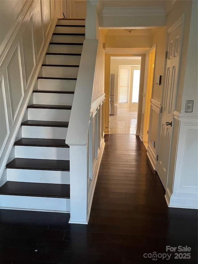 staircase featuring ornamental molding, hardwood / wood-style flooring, and a decorative wall