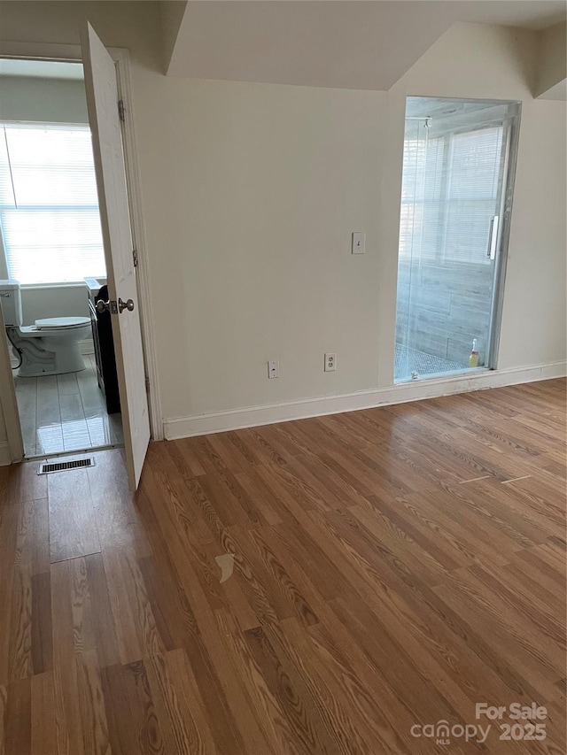 spare room with visible vents, baseboards, and wood finished floors