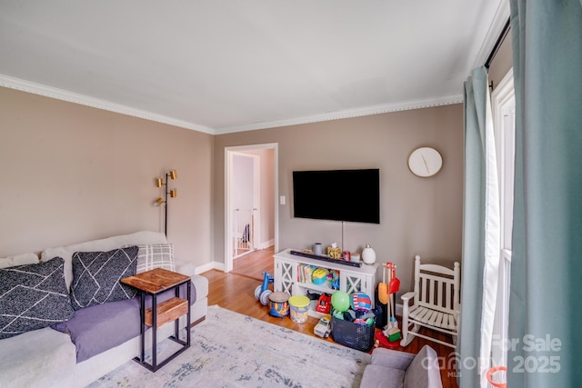 living room featuring ornamental molding, baseboards, and wood finished floors