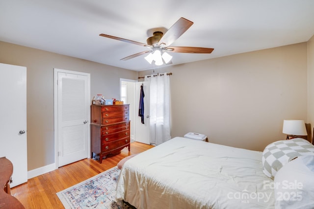 bedroom with a closet, baseboards, ceiling fan, and light wood finished floors