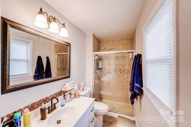 bathroom featuring toilet, a stall shower, and vanity