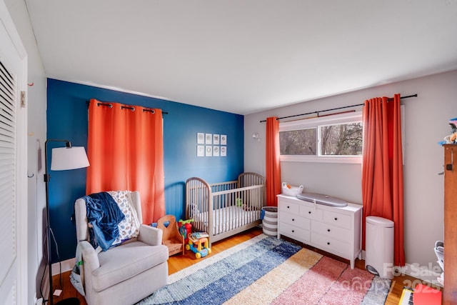 bedroom featuring a nursery area and wood finished floors