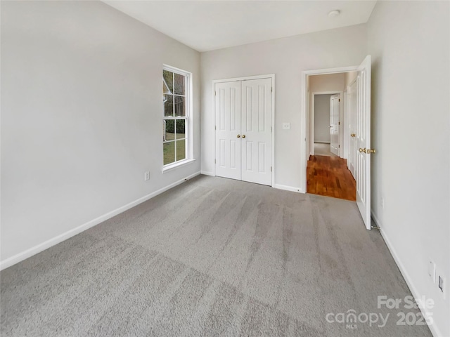 unfurnished bedroom with carpet floors, a closet, and baseboards