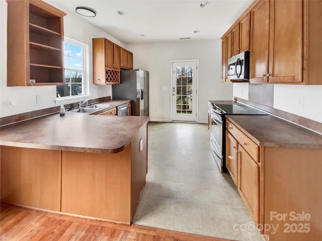 kitchen featuring a healthy amount of sunlight, brown cabinets, stainless steel appliances, and a sink