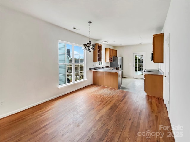 kitchen featuring visible vents, brown cabinetry, a peninsula, light wood-type flooring, and open shelves