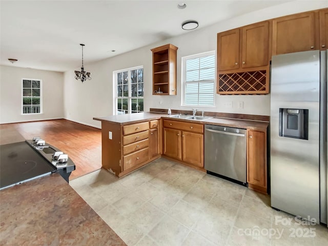 kitchen featuring stainless steel appliances, brown cabinetry, a peninsula, and open shelves