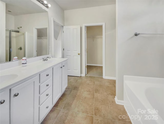 bathroom with double vanity, a shower stall, a walk in closet, and a sink