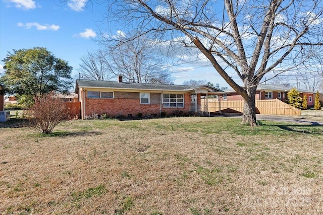 view of front of house with brick siding, a chimney, fence, cooling unit, and a front lawn