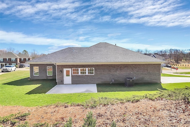 rear view of property featuring central AC, brick siding, a lawn, and a patio area