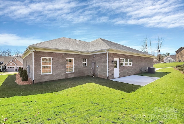 back of property with a shingled roof, a lawn, a patio, central AC, and brick siding