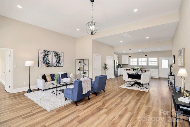 living room featuring light wood finished floors, recessed lighting, an inviting chandelier, and baseboards