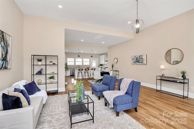 living room with a chandelier, recessed lighting, light wood-type flooring, and baseboards