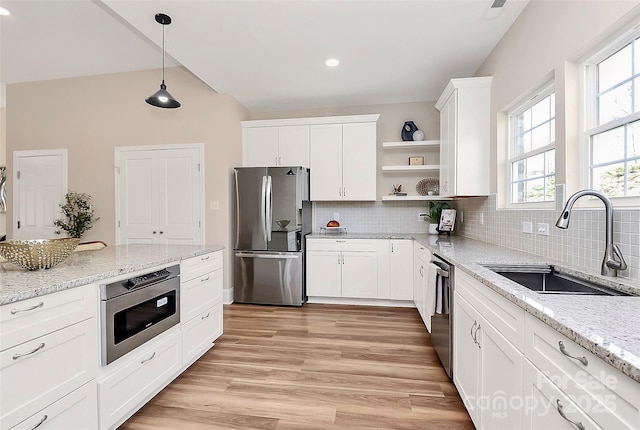 kitchen with open shelves, appliances with stainless steel finishes, light wood-style floors, white cabinets, and a sink