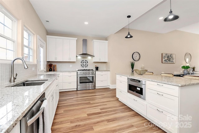 kitchen with high end stainless steel range oven, a sink, wall chimney range hood, light wood-type flooring, and dishwashing machine