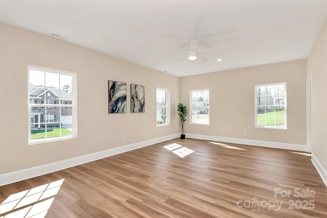 unfurnished room with light wood-type flooring, a ceiling fan, and baseboards