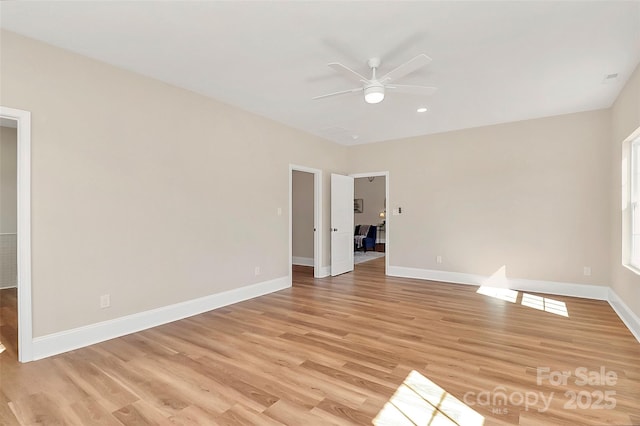 spare room featuring ceiling fan, light wood-style flooring, and baseboards