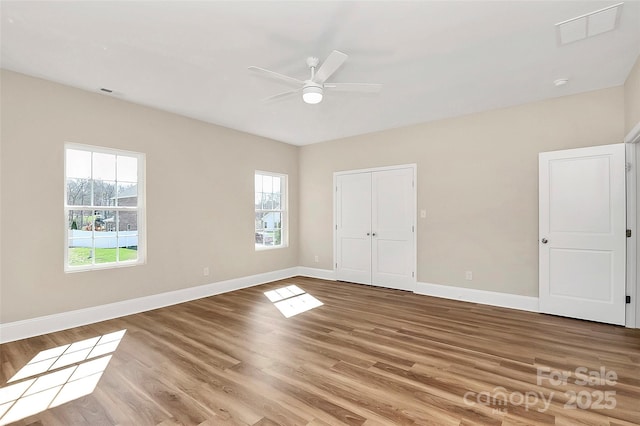 unfurnished bedroom with wood finished floors, visible vents, and baseboards