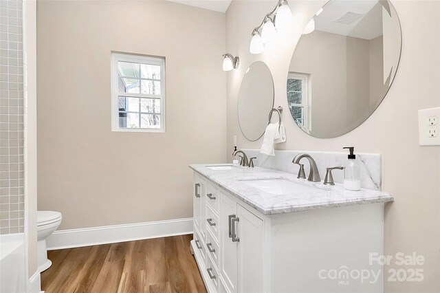 bathroom with baseboards, a sink, toilet, and wood finished floors