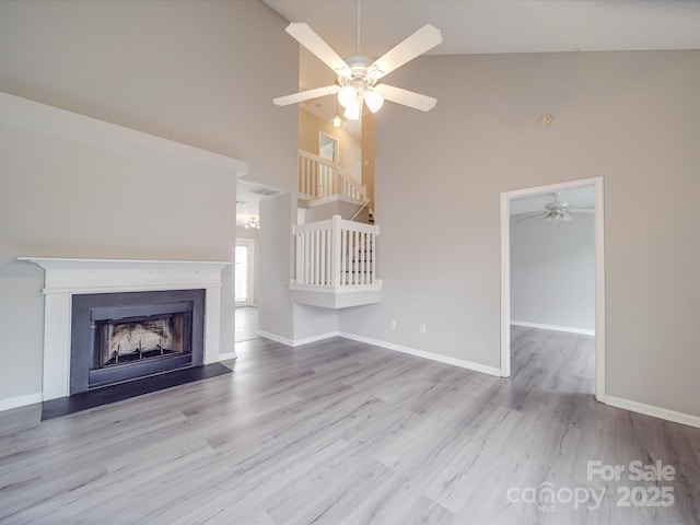 unfurnished living room featuring ceiling fan, a fireplace, wood finished floors, and baseboards