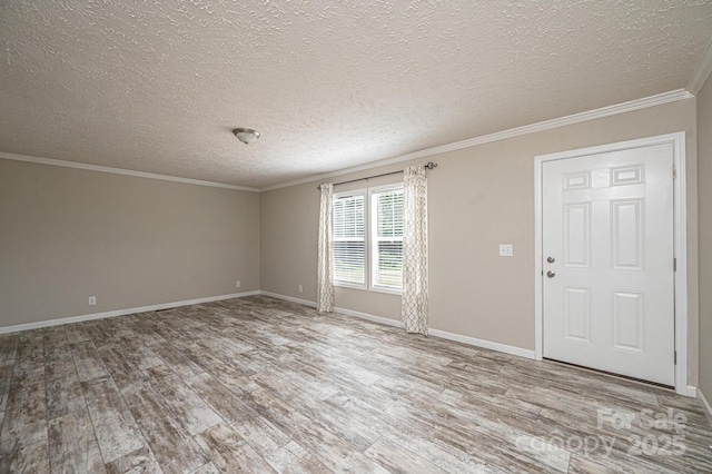 unfurnished room featuring ornamental molding, a textured ceiling, baseboards, and wood finished floors