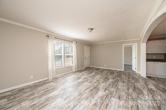 unfurnished living room featuring light wood finished floors, arched walkways, and ornamental molding