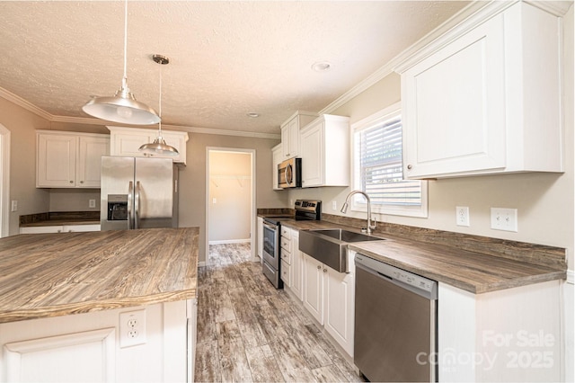 kitchen with white cabinets, crown molding, stainless steel appliances, and a sink