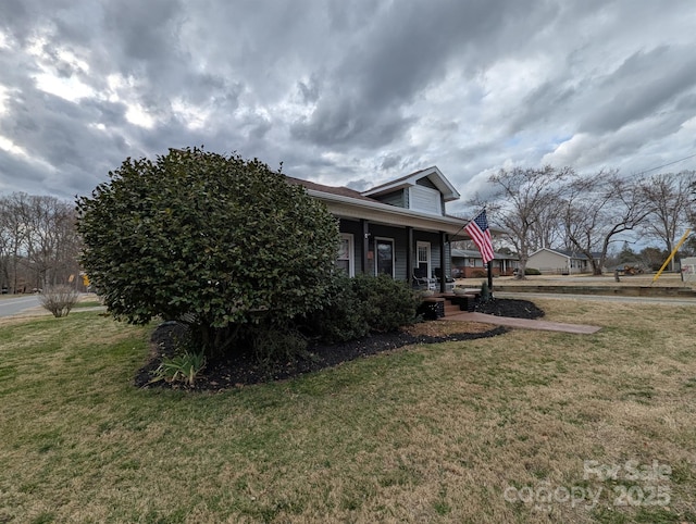 view of side of home featuring covered porch and a yard