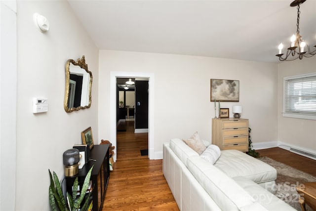 living area with a chandelier, baseboards, and wood finished floors